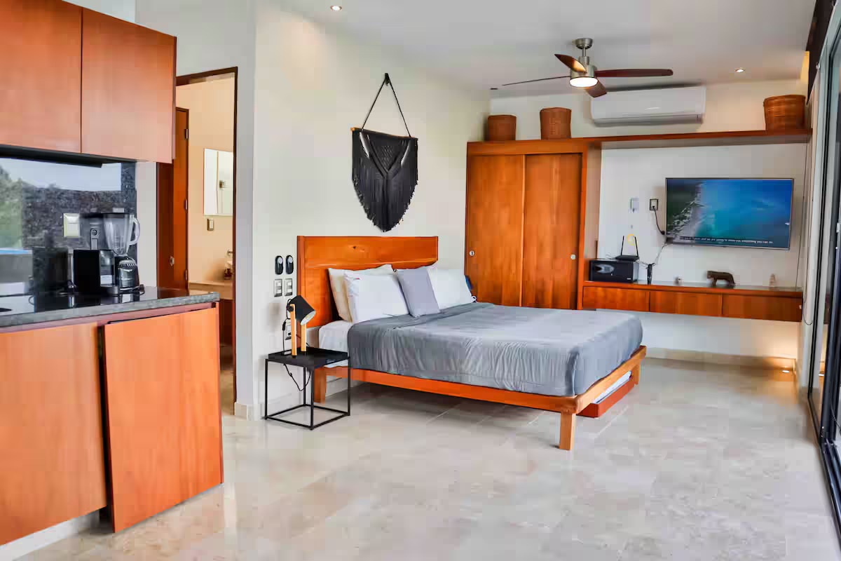 Bedroom with macramé wall hanging and kitchen